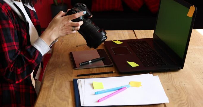 Photographer female working in a creative office holding camera, at desk and retouch photo
