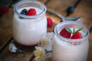 yoghurt with raspberries and blueberries on wooden background