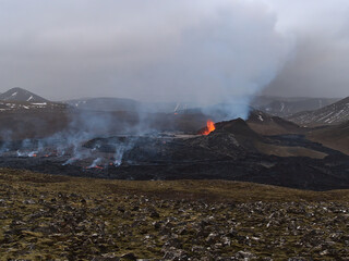 Beautiful view of erupting volcano in Geldingadalir valley near Fagradalsfjall mountain, Grindavík, Reykjanes peninsula, southwest Iceland ejecting hot lava with with dangerous fumes on cloudy day.