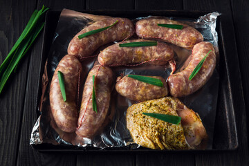 Raw meat sausage and ham on a Sheet pan is prepared for baking in the oven. The national meat dish is prepared before the holidays