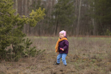 Obraz premium a small child with a toy in his hands stands near a tree and dances
