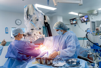 Modern neurosurgey in professional hospital. Male surgeon with assistance working in operation room.