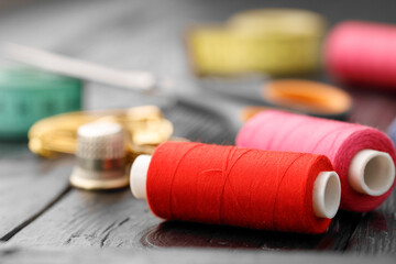 Fototapeta na wymiar Colorful sewing utensils on black wooden surface