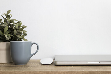 Grey coffee cup, computer, mouse mock up on table over the white wall.