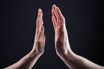Two Caucasian hands, male and female, on a dark background prepared to touch each other. High-five...