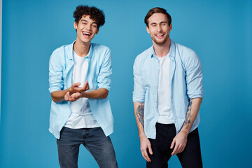 curly guy in shirt and blond man on blue background chatting friends cropped view