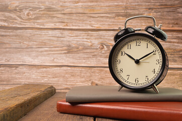 Naklejka premium Alarm clock and notebooks on wooden board. Conceptual image.
