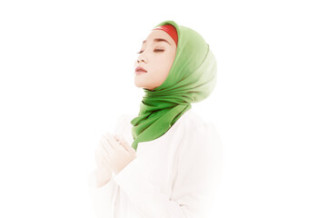 Asian Muslim woman in a veil sitting while raised hands and praying