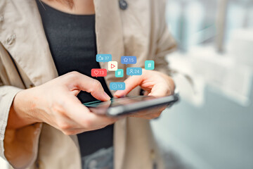 Hands of woman using a social media marketing concept on mobile smartphone with notification icons of love, like, message, comment and hashtag.