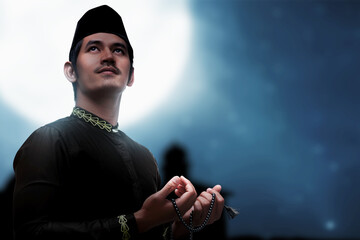 Asian Muslim man praying with prayer beads on his hands