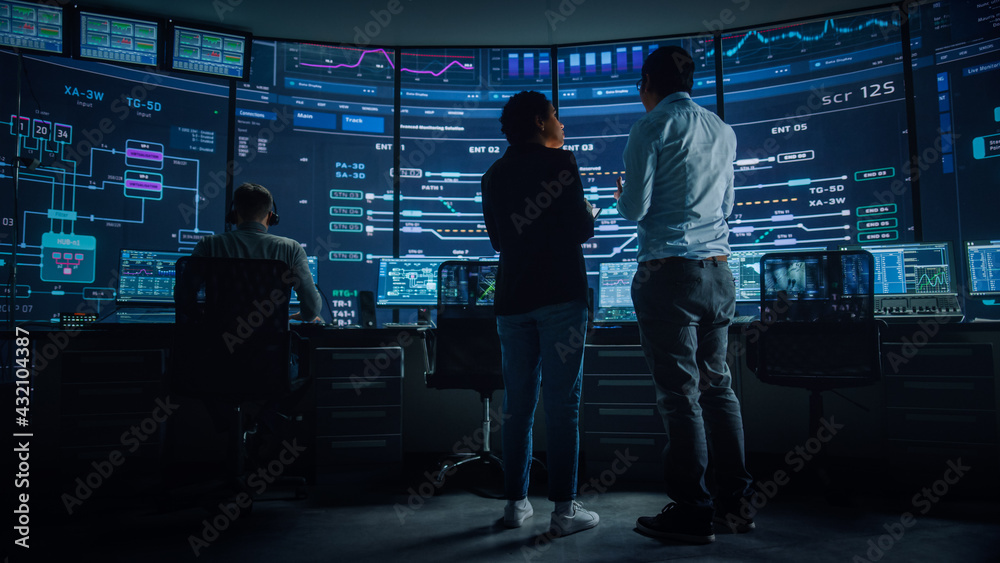 Fototapete In the System Control Room Project Manager and IT Technical Engineer Have Discussion, they're surrounded by Multiple Monitors with Graphics. Big Monitor Shows Interactive Server Blockchain Info.
