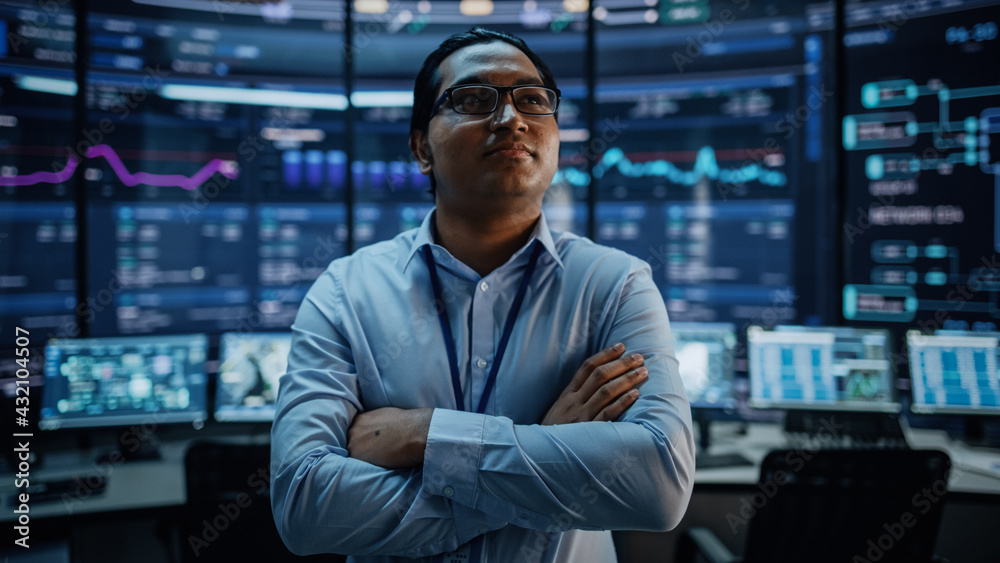 Poster Portrait of Professional Indian IT Technical Support Specialist or Software Developer Crossing Arms on Camera in a Modern Monitoring Control Room Full of Computer Displays with Technological Data.