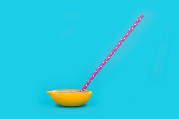 Lemon cut in half with straw on pastel blue background. Summer fresh juice concept.