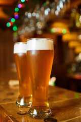 Two glasses of fresh foamy beer on the bar counter