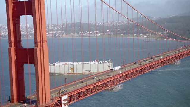 Cars and cargo ship passing by the Golden Gate Bridge in San Francisco 