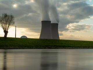 Nuclear power plant against sky by the river at sunset