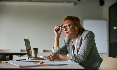 Female adjusting her glasses while reading paper records