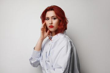 Young caucasian woman with red hair posing over grey background. Isolated.