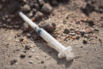 Dropped used syringe with needle on the ground, drug addict. Threat of drug addiction concept
