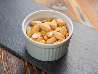 peeled almonds fried with salt in a small Cup on a black stone Board