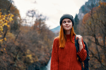 woman hiker in autumn forest near river mountains travel