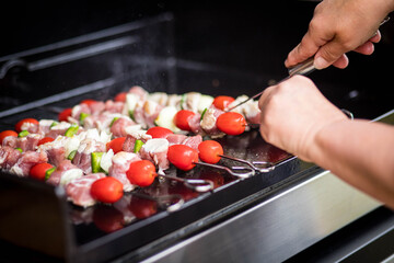 grillades de Brochettes de poulet et tomate sur une plancha qui cuisent 