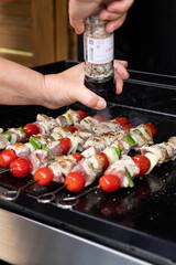 grillades de Brochettes de poulet et tomate sur une plancha qui cuisent 