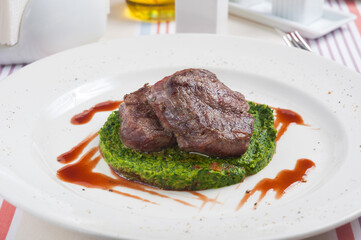 the steak of beef on a bed of spinach in a restaurant