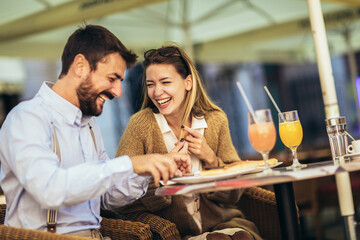 Young happy couple eating pizza for lunch in a restaurant
