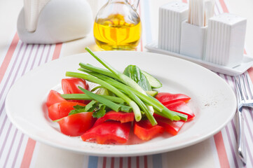 tomatoes cucumbers and green onions on a white plate