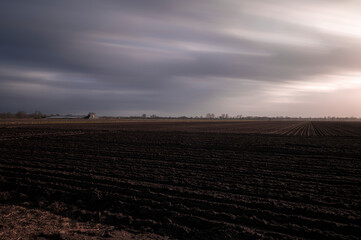 Obraz premium Clouds pass by over a farm and the fields