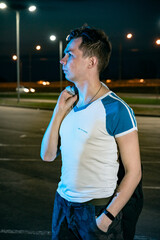 A young man in the parking lot at night amid the lanterns