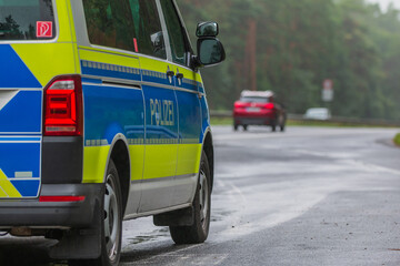 Fototapeta na wymiar Side view of a police car in an emergency stop next to the motorway. Police vehicle in blue and yellow paintwork with reflective strips. Police lettering on the body