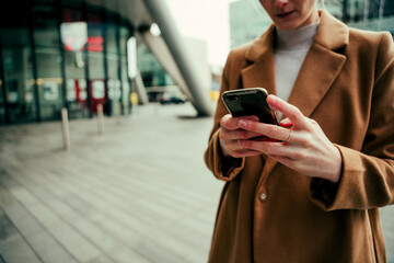 Close up caucasian business woman typing on cellular device standing in city