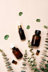 Glass brown bottles of essence or serum with natural eucalyptus leaves