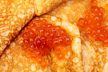 Pancake with red caviar as a background.