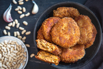 Vegetarian bean patties or cutlets on a black plate. Top view