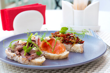 assorted bruschetta on a plate: with salmon, beef, vegetable. Selected focus.