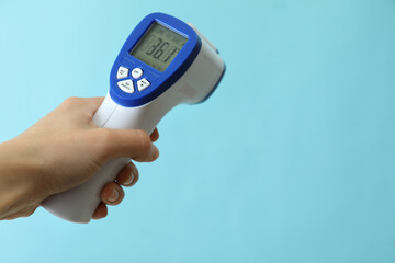 Female hand hold thermometer gun on blue background