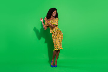 Full length portrait of excited cheerful dark skin girl look empty space partying isolated on green color background