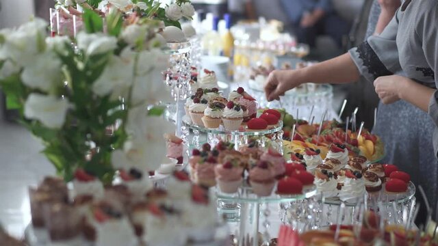 Stylish candy bar at the wedding reception. Sweet cakes and candies with muffins. People have fun and rest on the event. Beautiful festive decoration. Decor on the evening party.