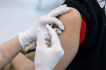 Obraz premium Close up doctor, nurse holding syringe making covid-19 vaccination injection dose in shoulder patient. Corona virus treatment side effect, close up view. Flu Vaccination Injection on Arm.