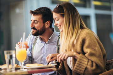 Young happy couple eating pizza for lunch in a restaurant