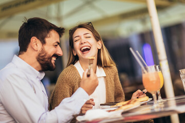 Young happy couple eating pizza for lunch in a restaurant