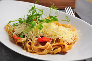 pasta with veal, vegetables and Parmesan on a white plate