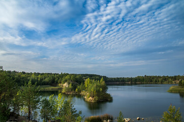 An old granite quarry and a formed lake with a sandy-rocky shore and tree-covered islands.