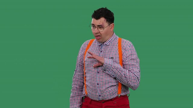 A man showing blah blah blah gesture. He listens to lies, nonsense, empty promises. Portrait of a man in glasses, a shirt with orange suspenders in the studio on a green screen. Slow motion. Close up.