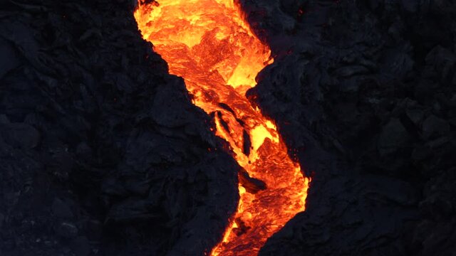 Tracking shot of flowing hot magma like a river during night. Geldingadalir Eruption in Iceland. Close up.