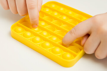 Close up shot of kids fingers on pop it fidget toy. Instrument for sequence, fine motor skills,...