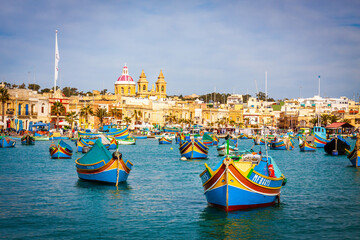 Obraz na płótnie Canvas malta - marsaxlockk port filled with typical boats called luzzu